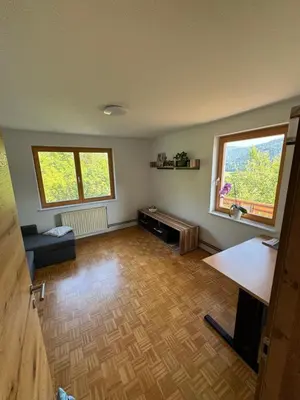 an empty living room with two windows and a wooden floor at Apartma Petra in Selca