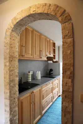 an archway in a kitchen with wooden cabinets at Apartma Saša in Zgornje Jezersko