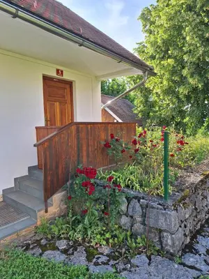 a garden in front of a house with red flowers at Mežnarija - Cerovec in Dolenjske Toplice