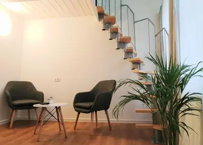 two chairs and a table in a room with a spiral staircase at Hotel garni Paleta in Škofja Loka