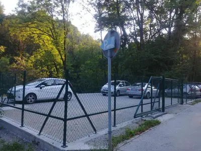 a stop sign in front of a fence with parked cars at Hotel garni Paleta in Škofja Loka