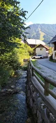 a stone fence next to a river next to a road at Mountain spring in Kranjska Gora