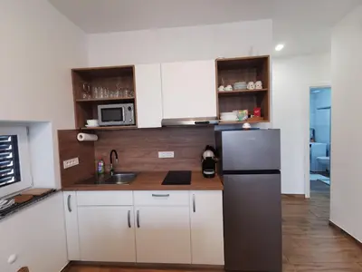 a kitchen with white cabinets and a stainless steel refrigerator at Apartma Gaber in Veliki Gaber