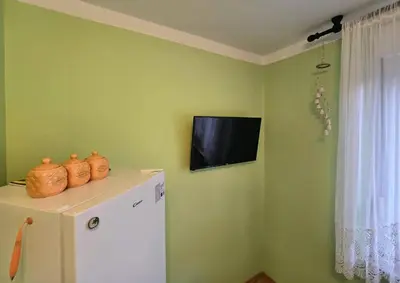 a television on the corner of a room with a refrigerator at At Granny's in Maribor