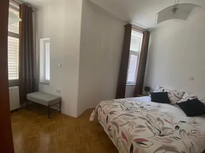 a bedroom with a bed and a chair and two windows at Apartma ROGATEC 2 in Rogatec