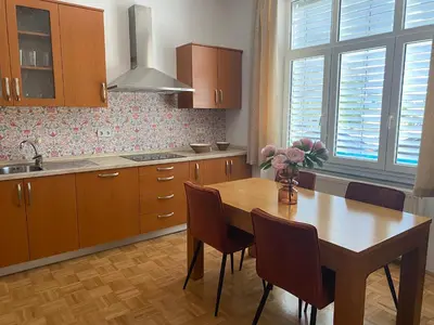 a kitchen with a wooden table with chairs and a vase of flowers at Apartma ROGATEC 2 in Rogatec