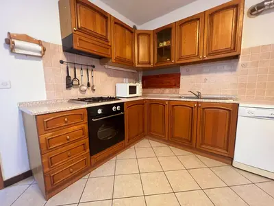 a kitchen with wooden cabinets and a black stove top oven at Apartma Suzy in Bovec