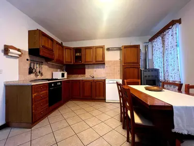 a kitchen with wooden cabinets and a table in it at Apartma Suzy in Bovec