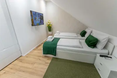 a small white room with a bed with green accents at GOLDEN OASIS Free Private Parking in Ljubljana
