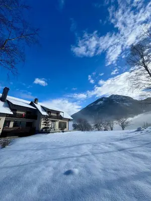 a house in the snow with a mountain in the background at Gaj pod brezami in Luče