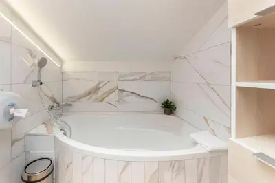 a white bathroom with a tub and a shower at Apartment MaLa in Bled