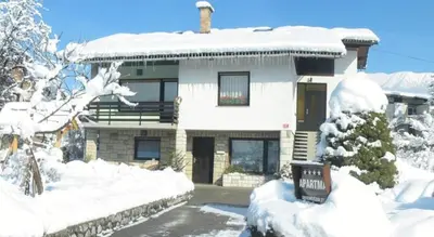 a house covered in snow with a sign in front of it at Apartment MaLa in Bled