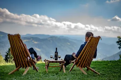 a man and a woman sitting in chairs with a table at Domačija Za robom in Cerkno