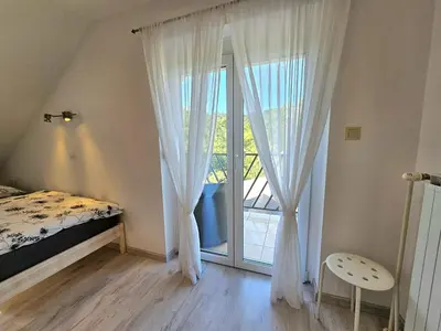a bedroom with a bed and a large window at Green Hill Apartments in Žirovnica