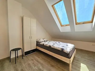 a bedroom with a bed and a cabinet and two windows at Green Hill Apartments in Žirovnica