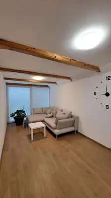 a living room with a couch and a clock on the wall at Wellness house ZoJa with outdoor sauna and hot tub in Boštanj