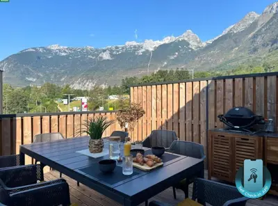 a table on a deck with a view of mountains at Lux Apartment in Bovec