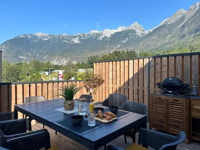 a table on a deck with a view of mountains at Lux Apartment in Bovec