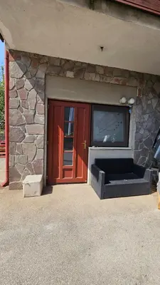 a red door with a tv and a stone wall at Puci Apartment in Šmarje-Sap