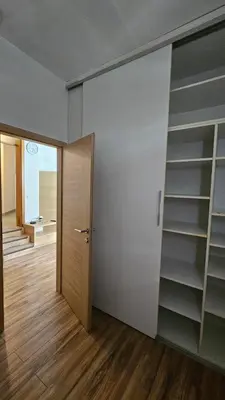 a hallway with a door and a room with shelves at Puci Apartment in Šmarje-Sap