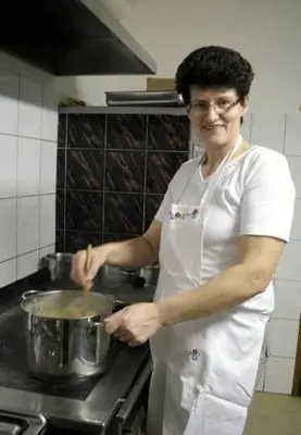 a woman in a kitchen stirring a pot at Tourist Farm Ob izviru Krupe in Semič