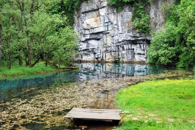 a wooden bench sitting in the middle of a river at Tourist Farm Ob izviru Krupe in Semič