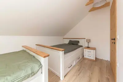 a bedroom with a white bed and a wooden floor at Luxury Villa TINKA in Zgornje Gorje