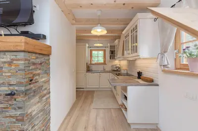 a kitchen with white cabinets and a stone wall at Luxury Villa TINKA in Zgornje Gorje