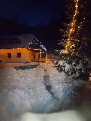 a house in the snow at night with lights at apartma Pohorc - Macesen in Pohorje