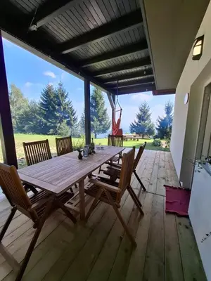 a wooden table and chairs on a deck at apartma Pohorc - Macesen in Pohorje