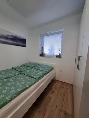 a bedroom with a bed and a window at apartma Pohorc - Macesen in Pohorje