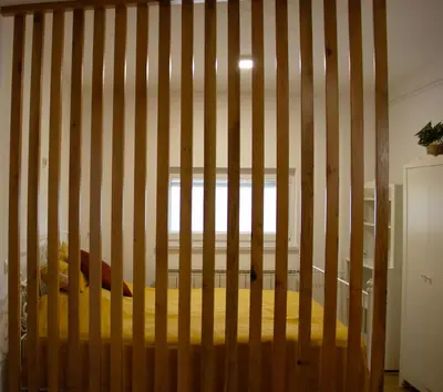 ajar view of a bed in a wooden crib at Poppqi's home in Polzela