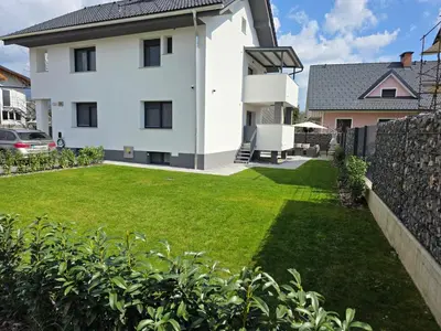 a white house with a yard with green grass at Erika's home - apartment house in Šenčur