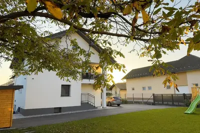 a white building with a car parked in a driveway at Erika's home - apartment house in Šenčur