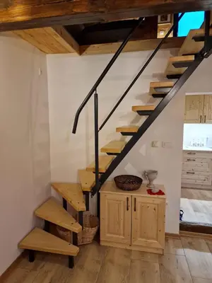 a staircase in a room with wooden floors and a kitchen at Cottage in Stara Gora 45720 in Debenec