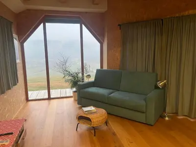 a living room with a green couch and a large window at Lojzov toplar Modern haystack in Velike Lašče