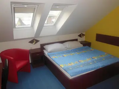 a bedroom with a bed and a red chair at Hotel Pri Belokranjcu in Novo Mesto
