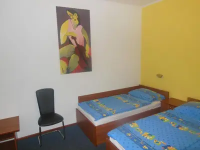 a room with two beds and a chair and a painting at Hotel Pri Belokranjcu in Novo Mesto