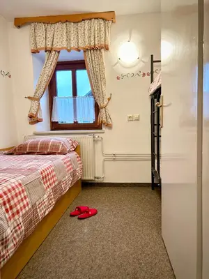 a bedroom with a bed and a window and red slippers at Al-Pine Apartment in Kranjska Gora