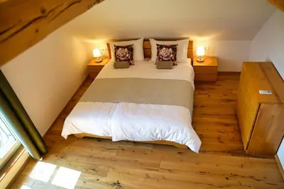 a bedroom with a large bed with wooden floors and two lamps at House Tinka Bled in Bled