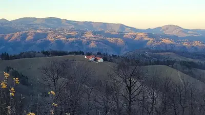 a house on a hill with mountains in the background at Apartma Tanja bike-friendly in Limbuš