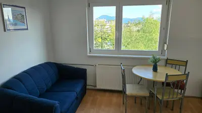 a living room with a blue couch and a table at Garsonjera in Ljubljana