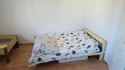 a small bed with a comforter on it in a room at Garsonjera in Ljubljana