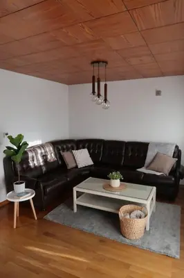 a living room with a black leather couch and a table at Cozzy cottage near Ljubljana in Višnja Gora