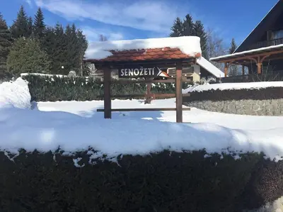 a snow covered bench in a yard with a sign at Cozzy cottage near Ljubljana in Višnja Gora