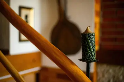a candle on a stand next to a staircase at Charming Bled Home - Big Garden, BBQ & Free Bikes in Bled