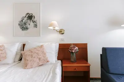 a bedroom with a bed and a vase of flowers on a night stand at Hotel Toplice - Terme Čatež in Čatež ob Savi