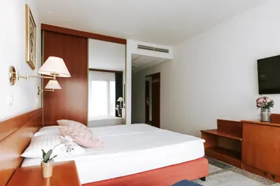 a bedroom with a white bed and a television at Hotel Toplice - Terme Čatež in Čatež ob Savi