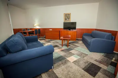 a living room with two blue couches and a tv at Hotel Toplice - Terme Čatež in Čatež ob Savi