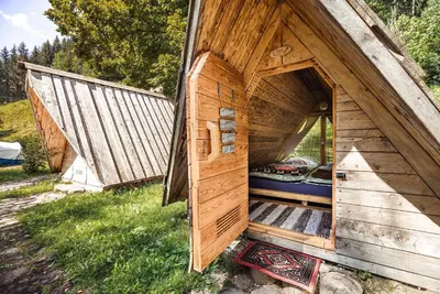 a small wooden house with a door in the grass at Camping & Glamping Jezersko ex Cvet Gora in Zgornje Jezersko
